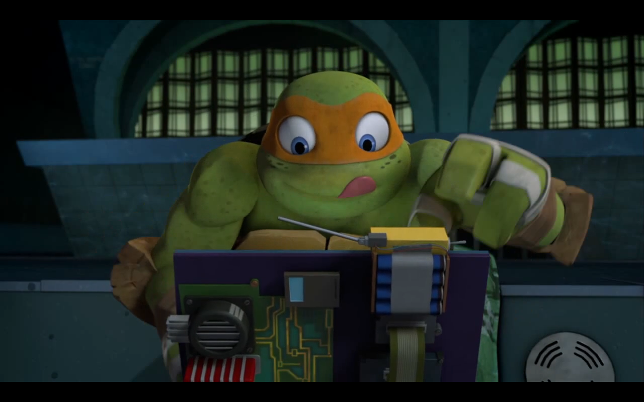 TMNT Mikey typing away on a laptop sitting on a couch in the turtles lair.